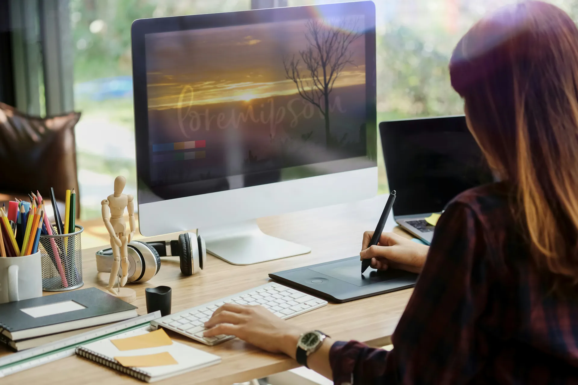Girl at desk with monitor, drawing tablet, and laptop for web design.