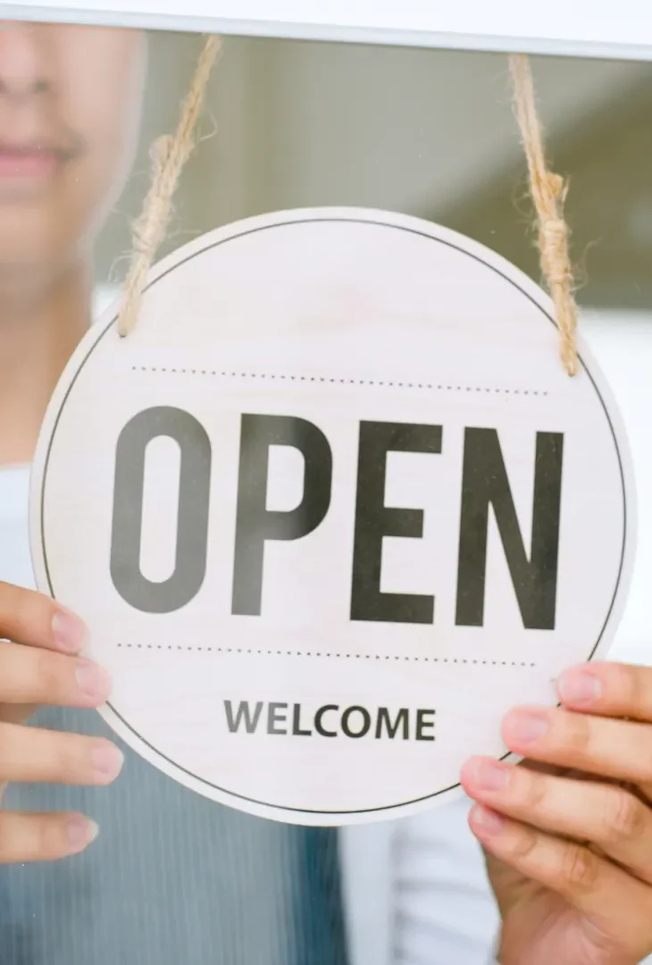 Young Man placing Open Welcome sign on store door